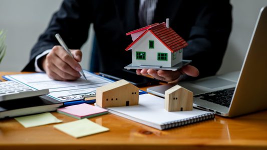 Close up house model with business man signs a purchase contract